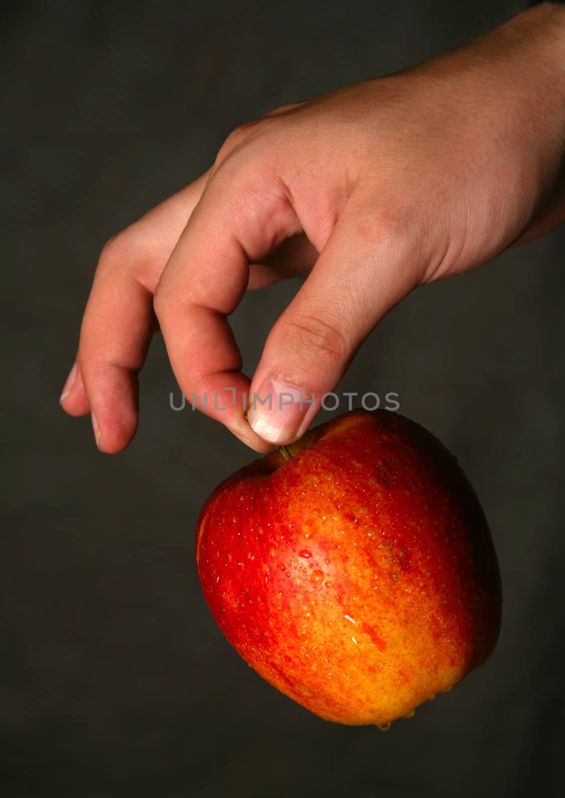 Man's hand with a red apple on a dark background