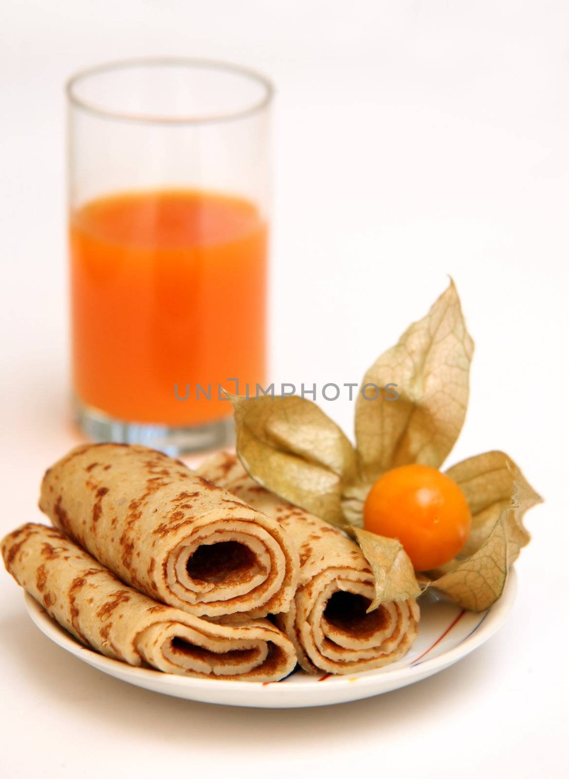 Pancakes on a plate and a glass with carrots juice