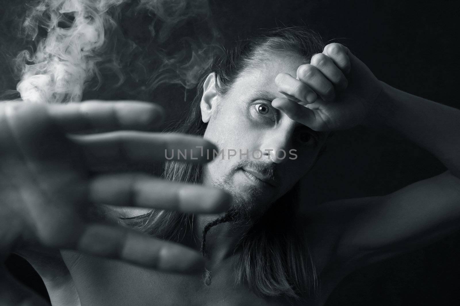 Portrait of the man closed by hands on a background of a smoke