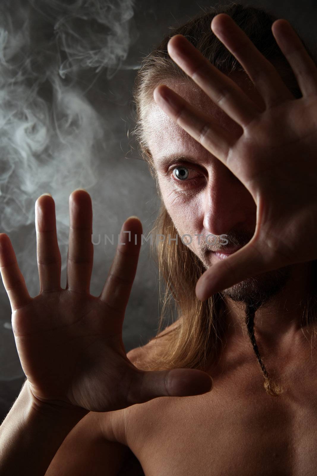 Portrait of the man closed by hands on a background of a smoke