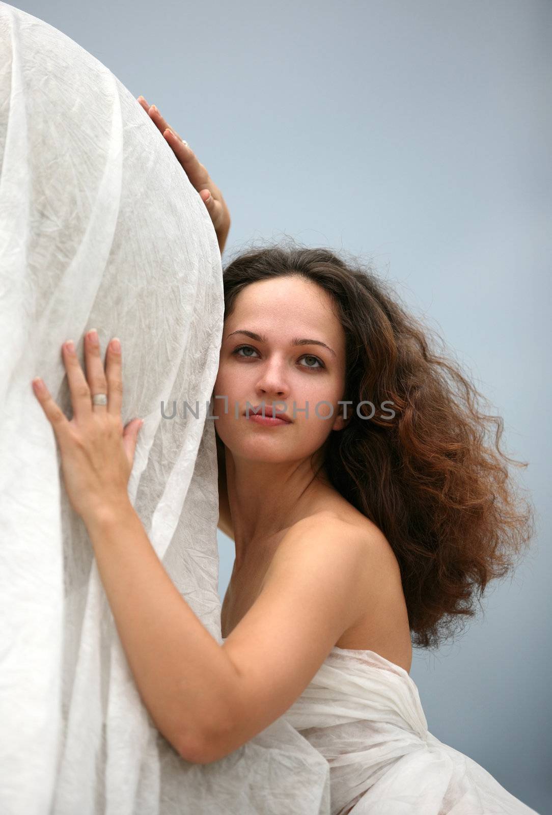 The girl in a white fabric on a background of the sky