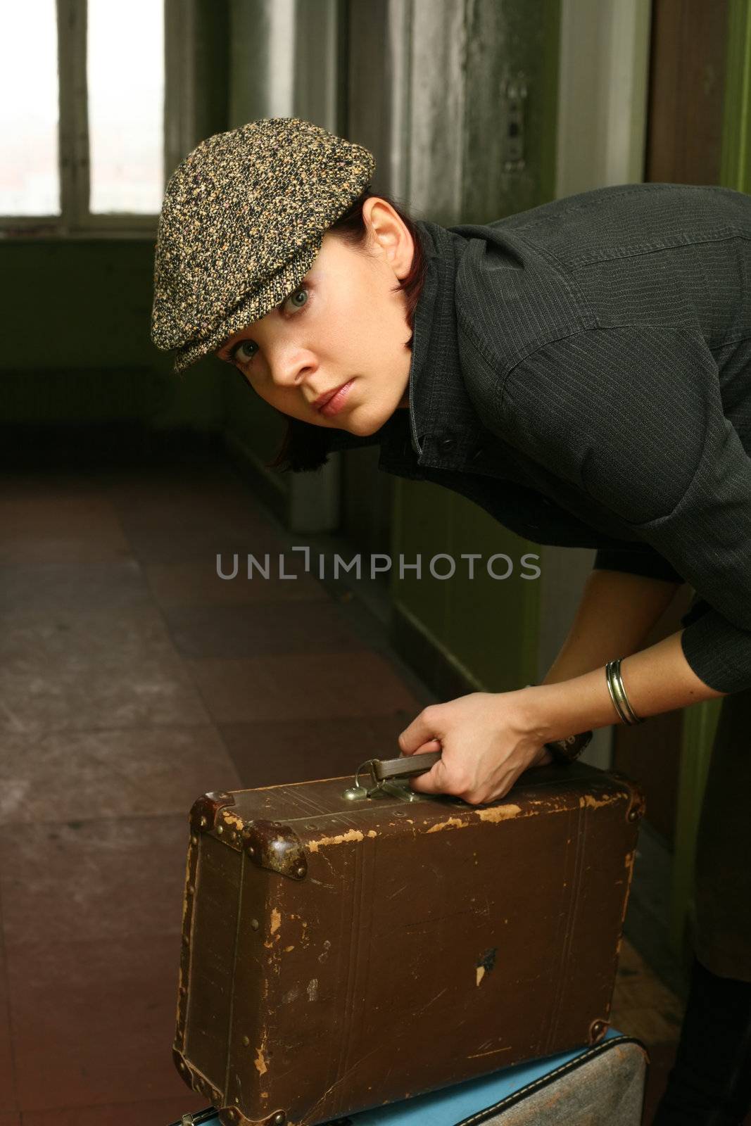 The beautiful woman in a cap with two old suitcases