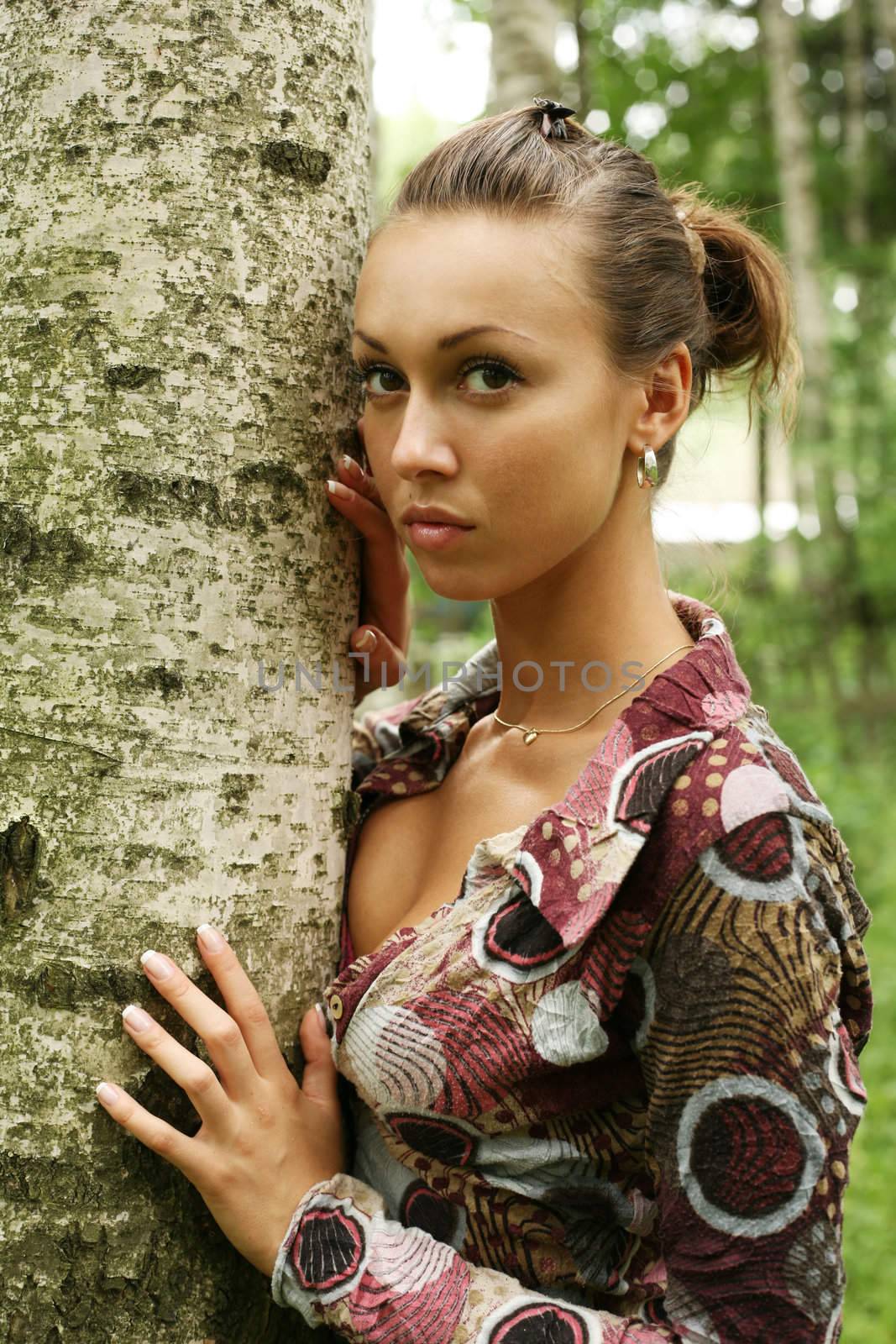 Young woman leaning against birch tree in forest