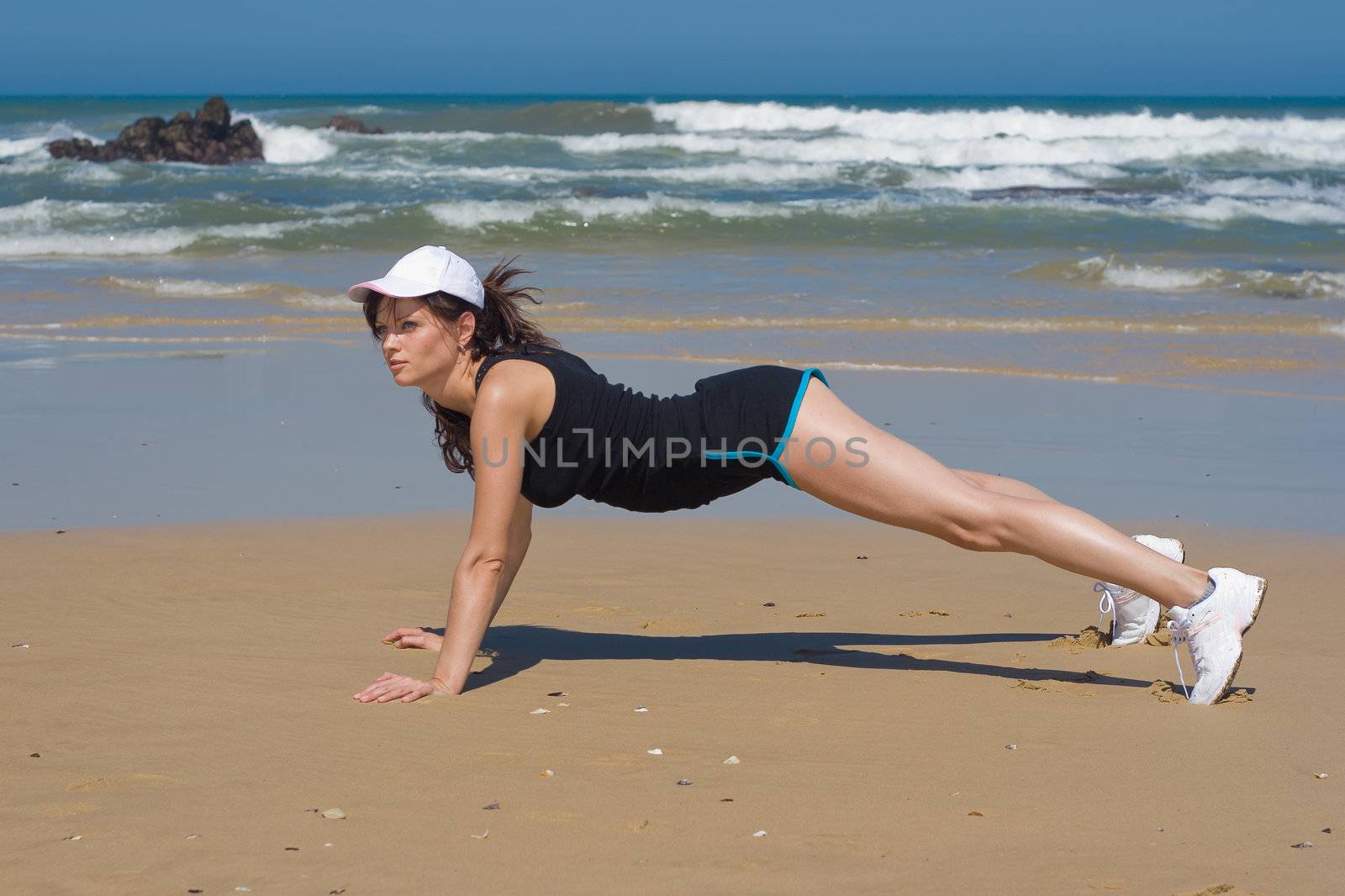 Fitness model doing push up exercises on the beach