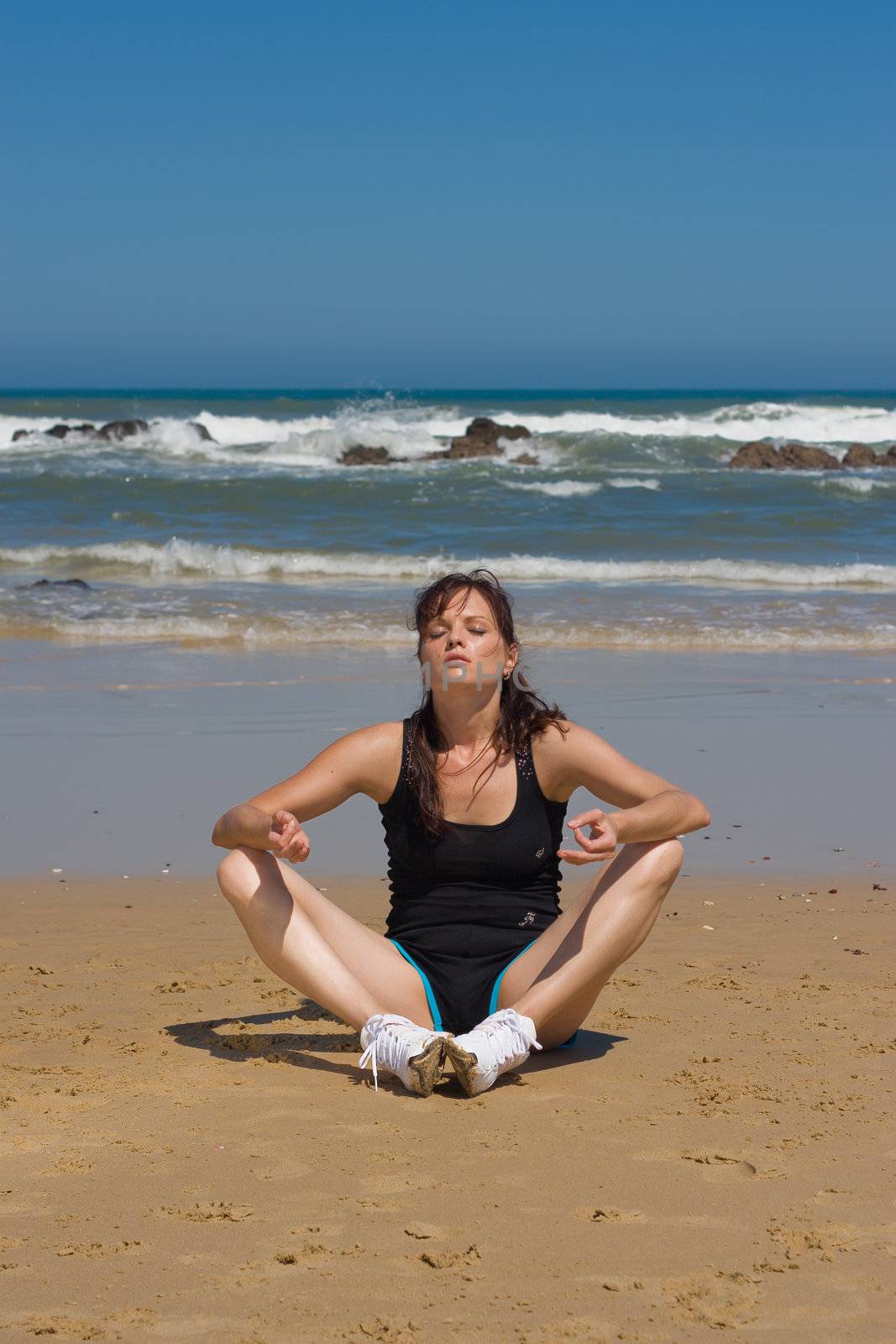 Yoga fitness model meditating on the beach
