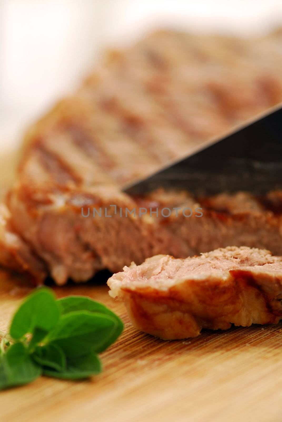 Grilled steak being cut on a cutting board, closeup