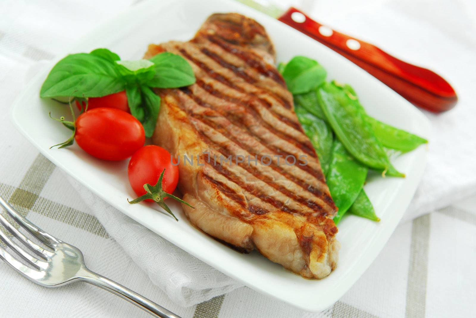 Grilled New York beef steak served on a plate with vegetables