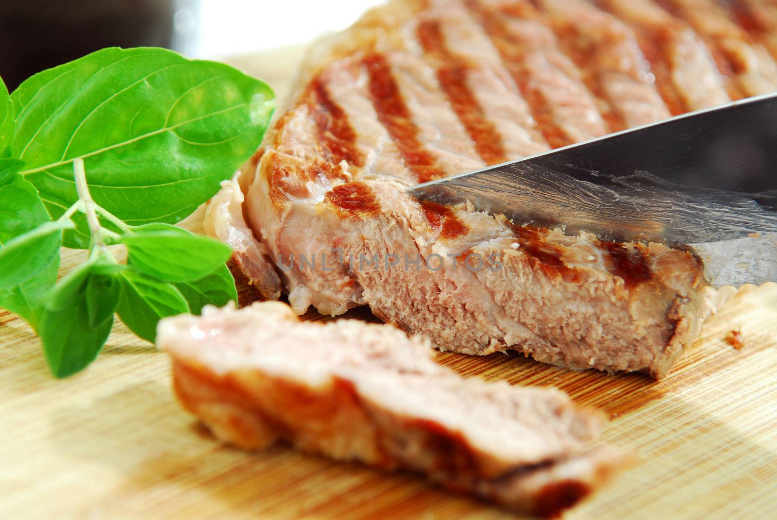 Grilled steak being cut on a cutting board, closeup