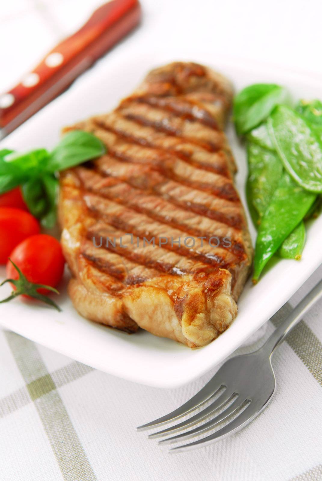 Grilled New York beef steak served on a plate with vegetables