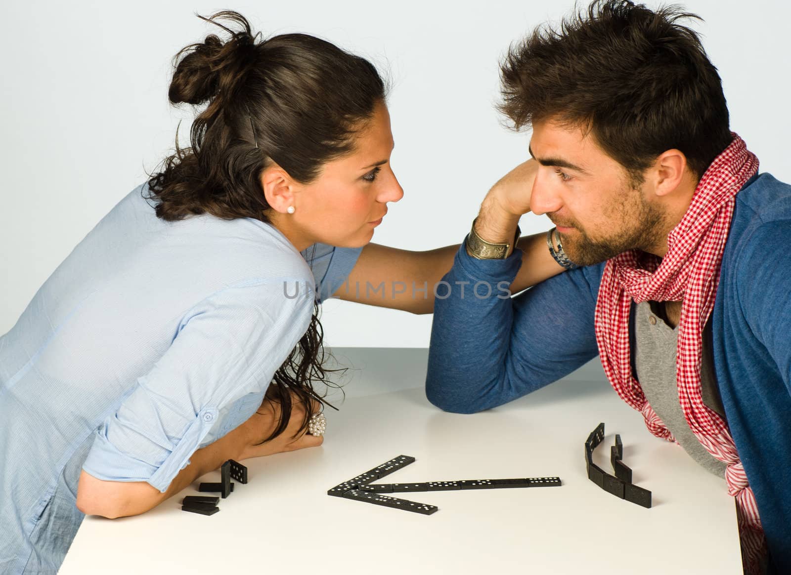 Couple in a playful mood with domino stones on the  table