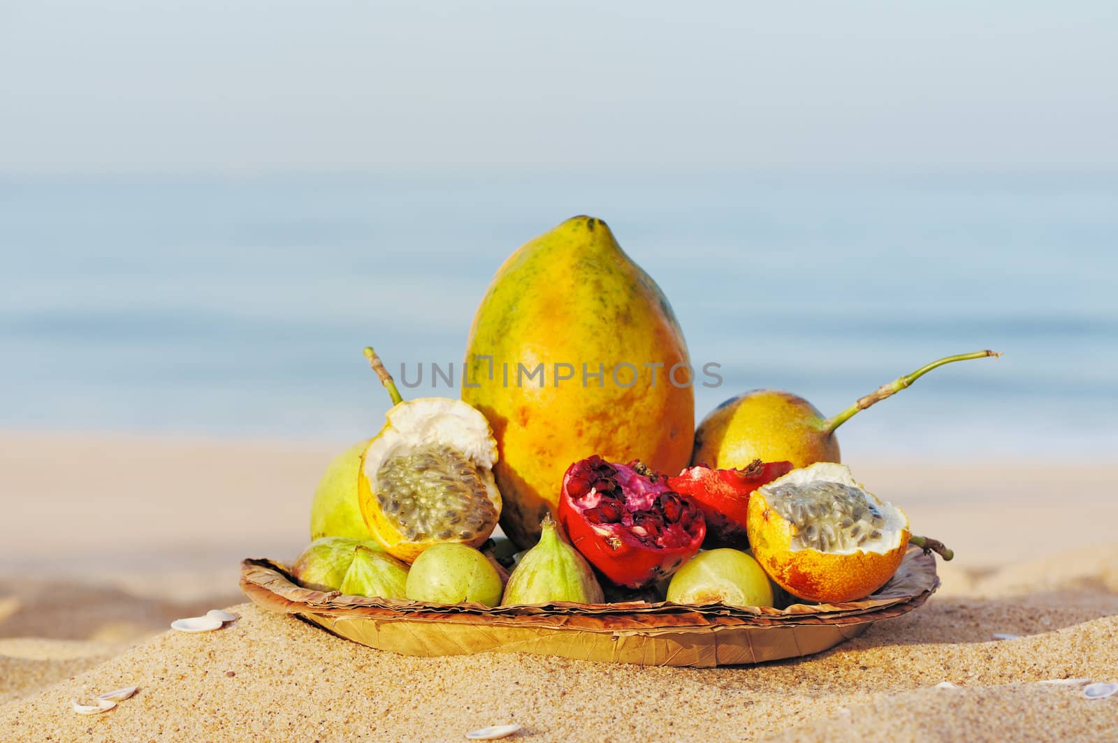 Exotic tropical fruit on the leaves plate, on the sandy beach