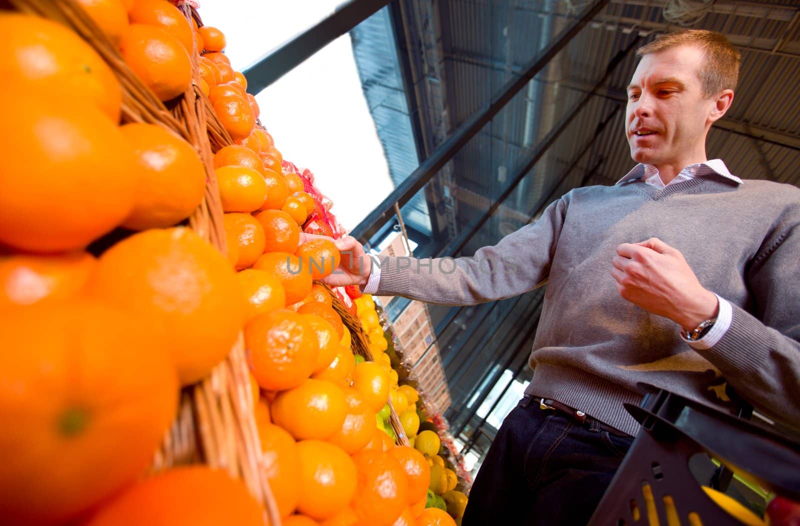 A man with a basket buying oranges and fruit at a grocery store