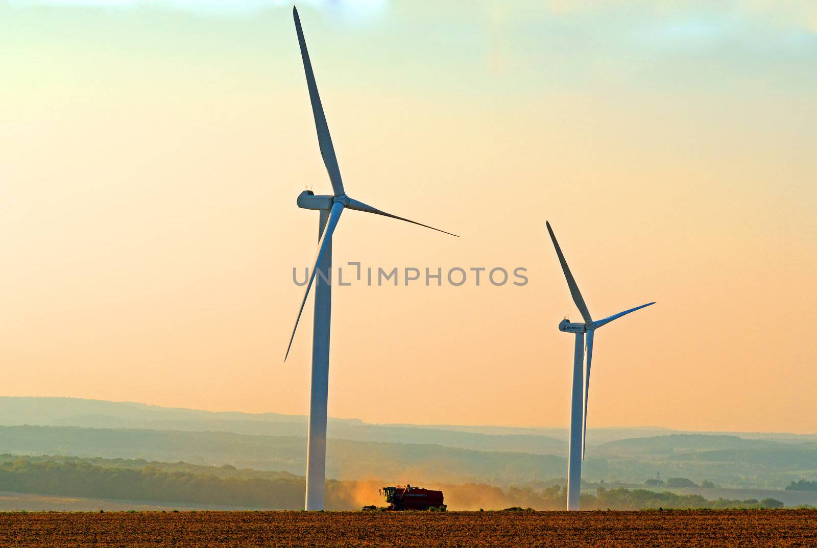 a combine harvester between two wind turbines