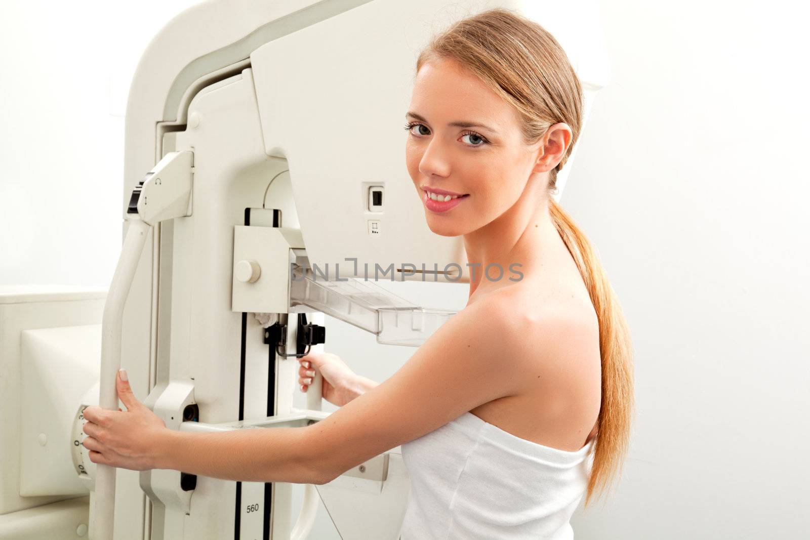 A young woman having taking a mammogram, looking at the camera