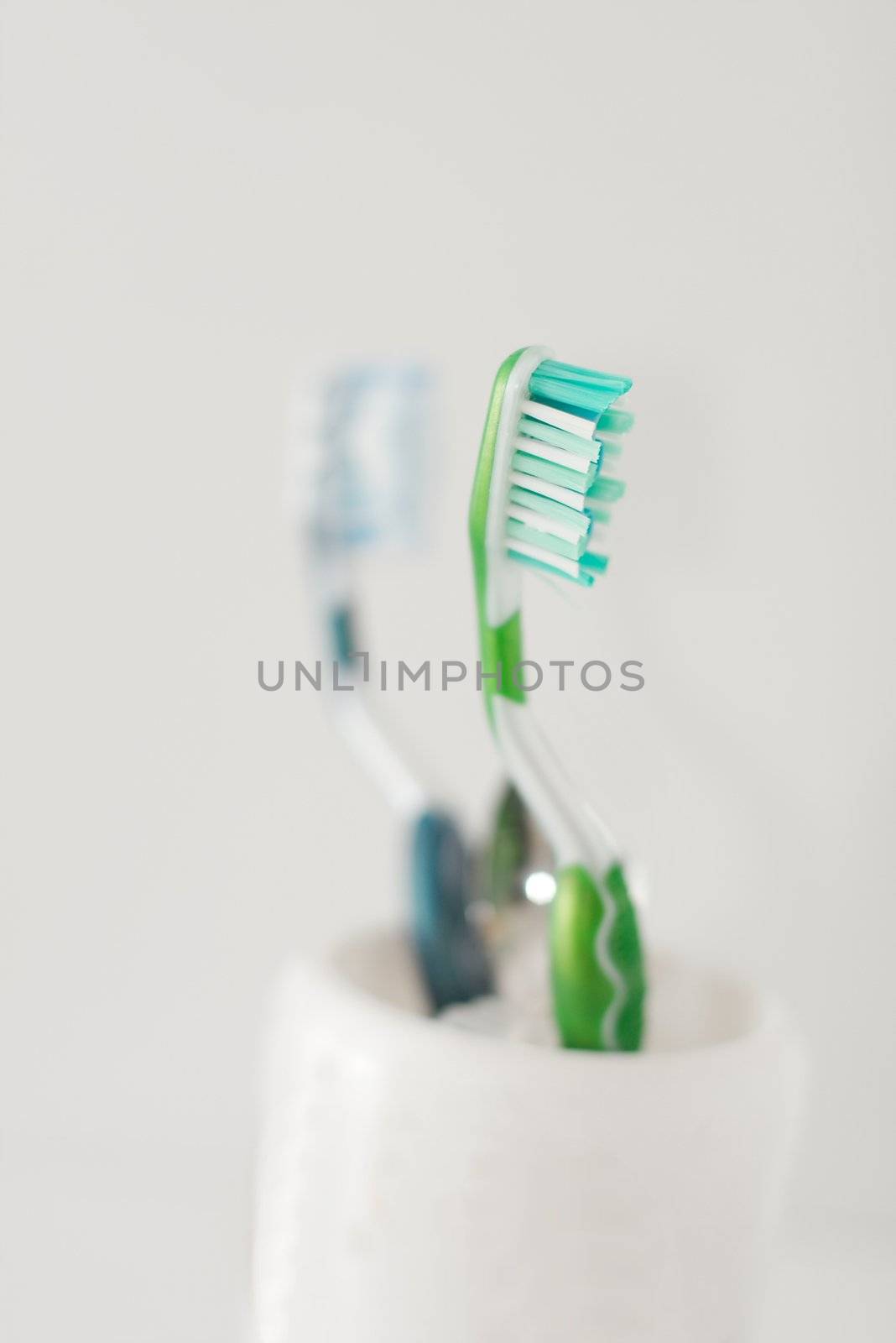 Tooth brushes in mug, one of them in focus
