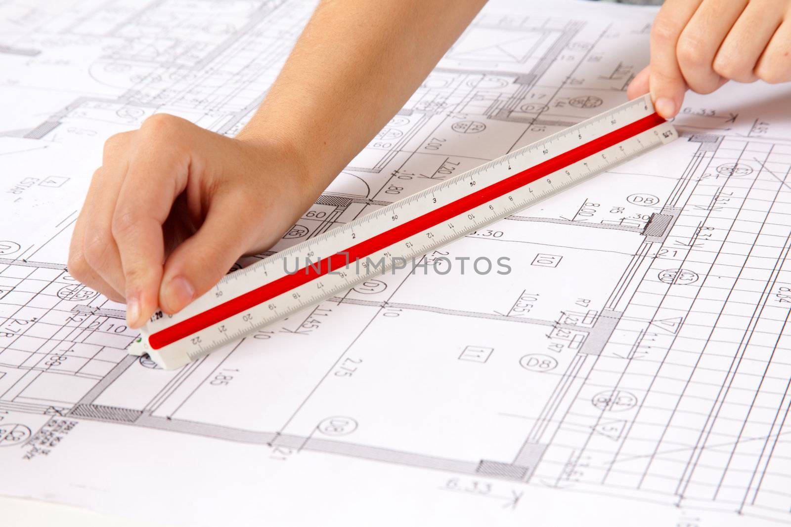 Two hands using a scale ruler on a set of blueprints