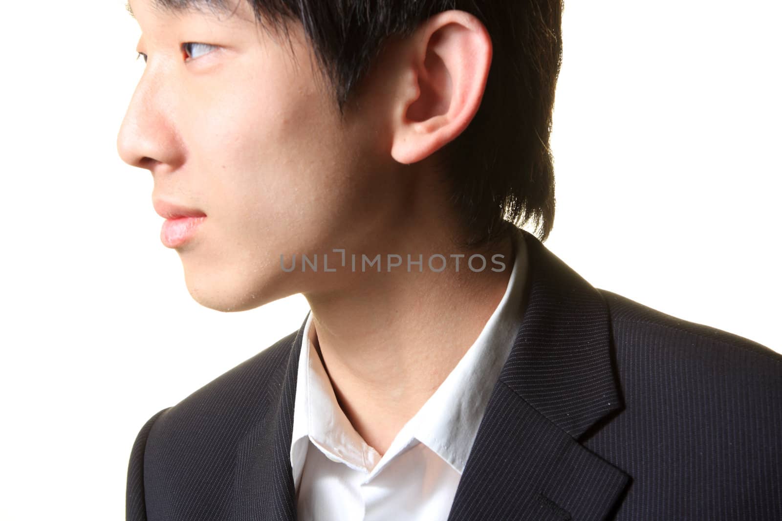 Young businessman standing and looking right on white background.