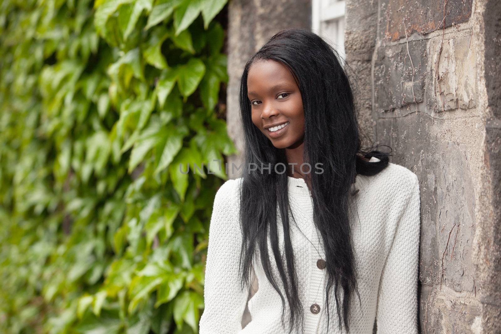 Smiling African American female standing in front of stone wall