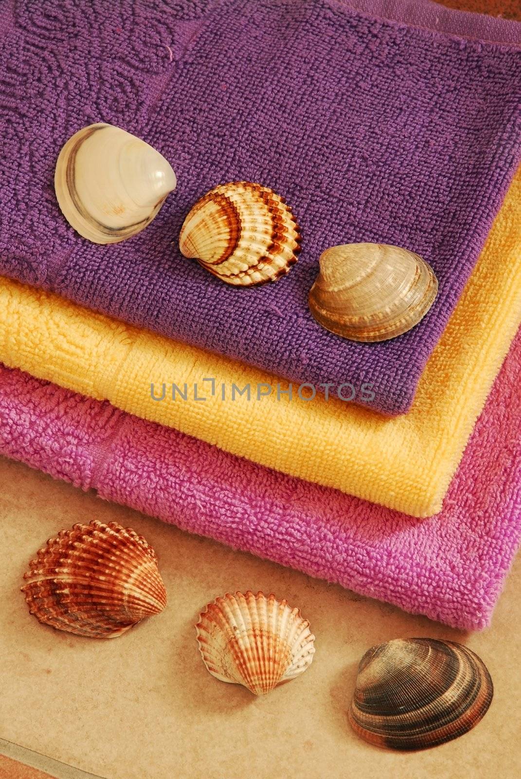 pile of new yellow, magenta and purple cotton towels with a shells