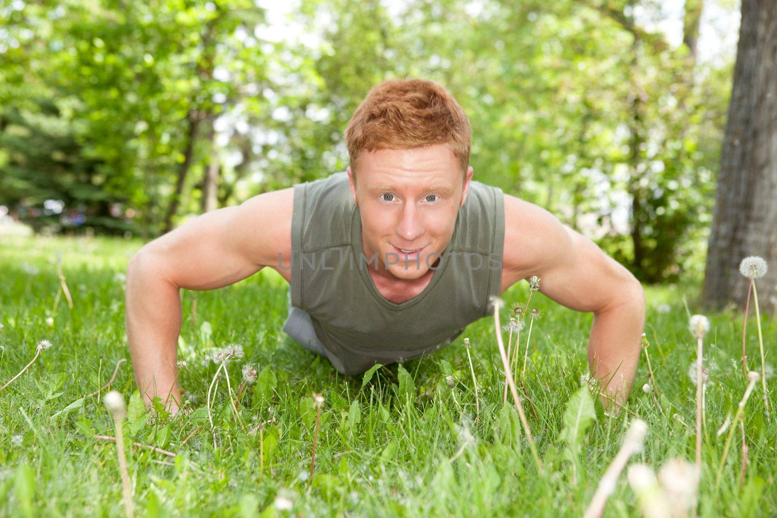 An attractive Caucasian man doing a push up outdoors