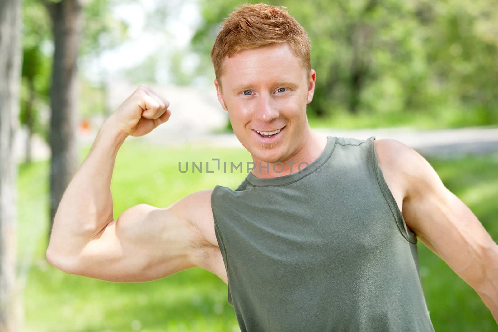 Athletic man showing muscles by leaf