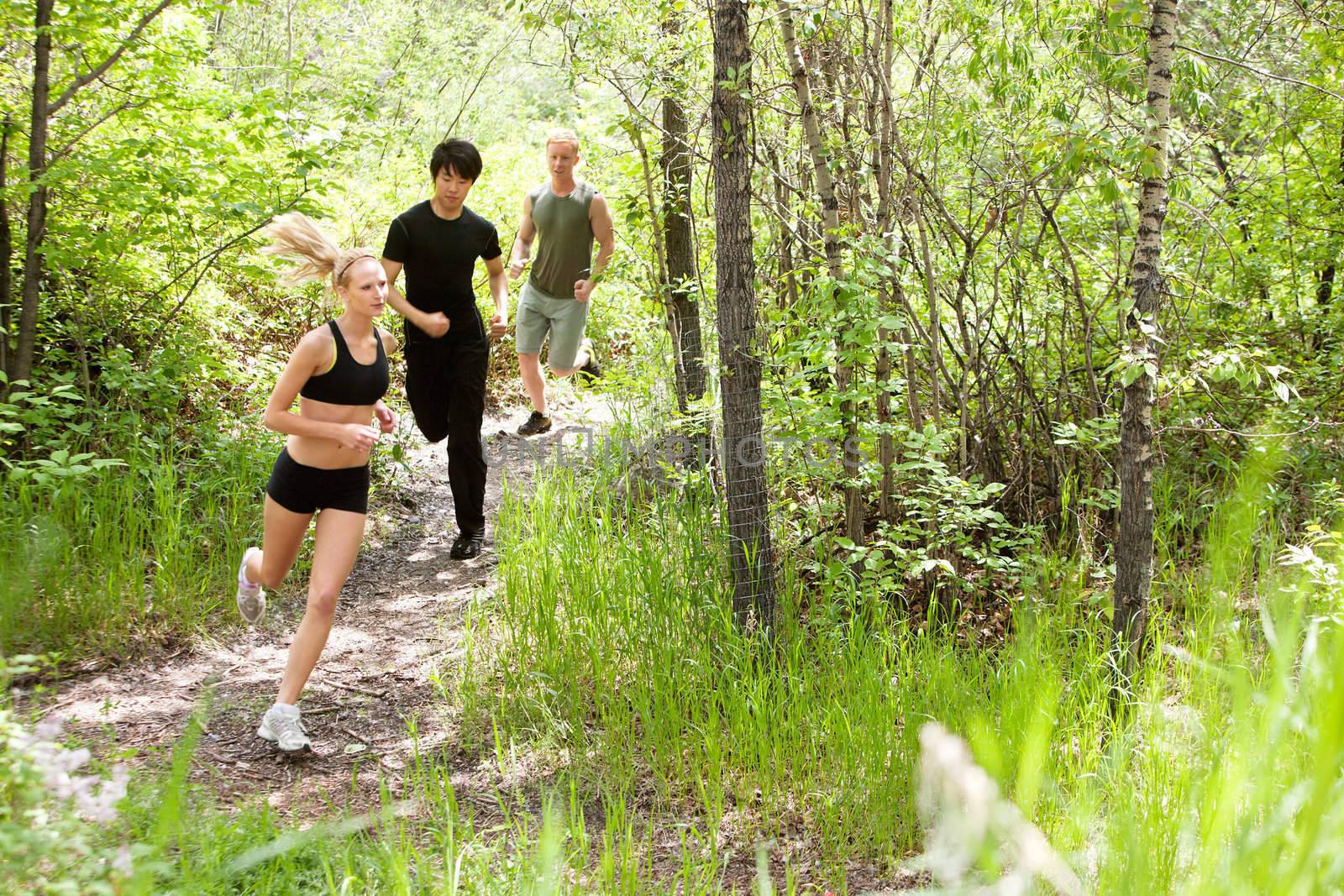 Three friends running in the forest on pathway