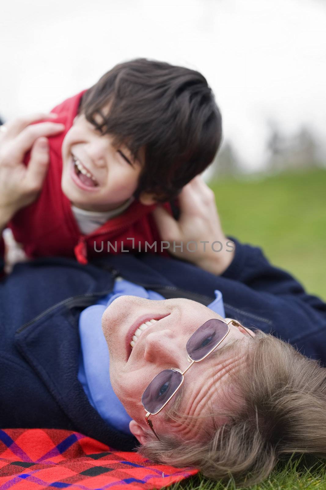 Father playing with disabled son on grass at park by jarenwicklund