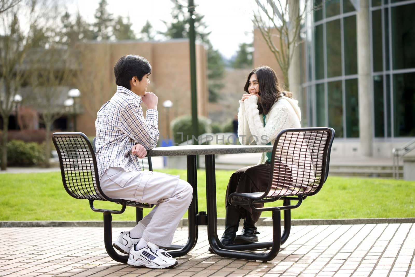 Two young teenagers sitting talking together outdoors