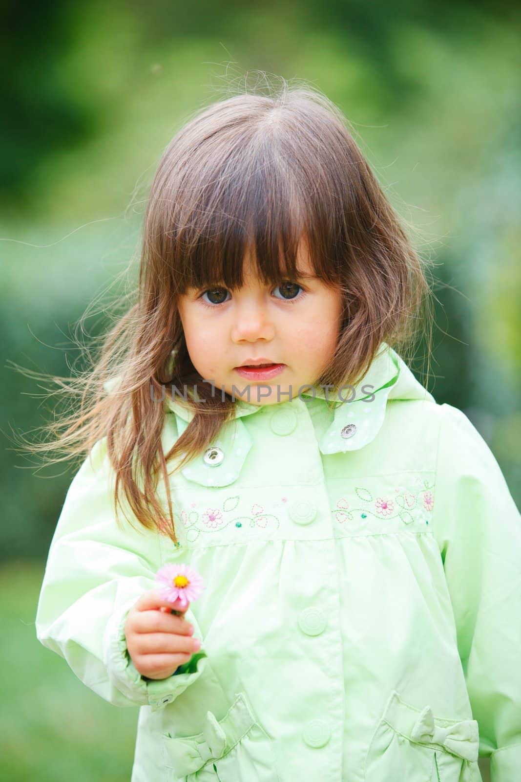 Clouse-up portrait pretty little girl in the park with a flower