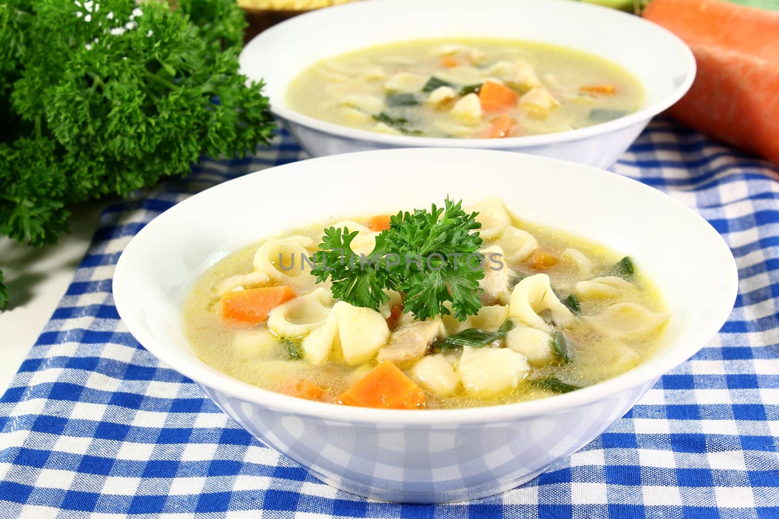 a cup of chicken soup with fresh vegetables