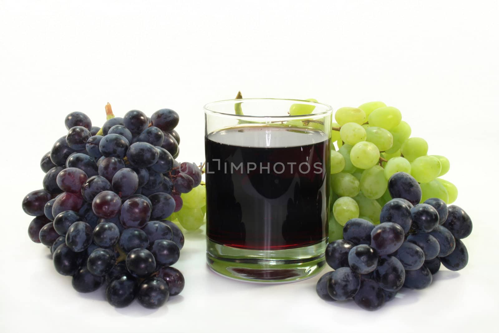 a glass of grape juice with light and dark grapes