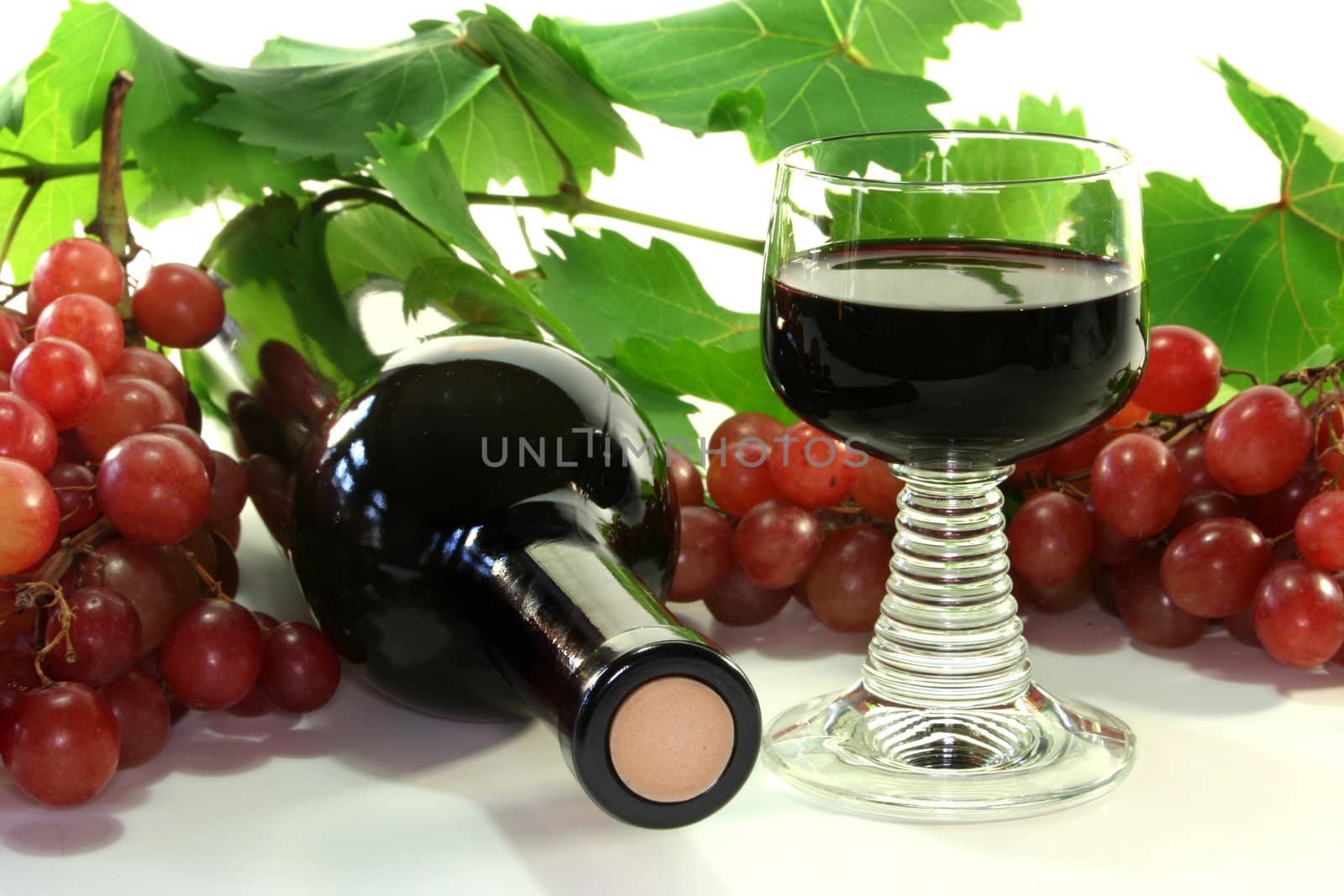 A bottle of red wine with grapes and leaves