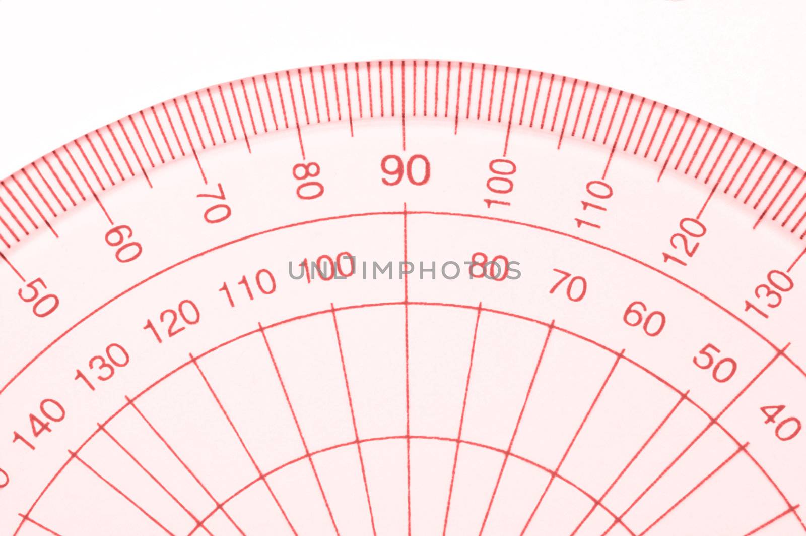Close Up capturing a portion of a transparent plastic protractor arranged over white.