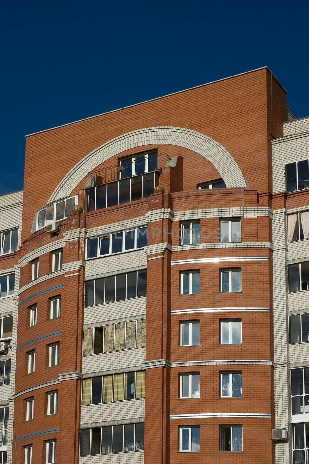 High multistory house of red and white bricks on sky background
