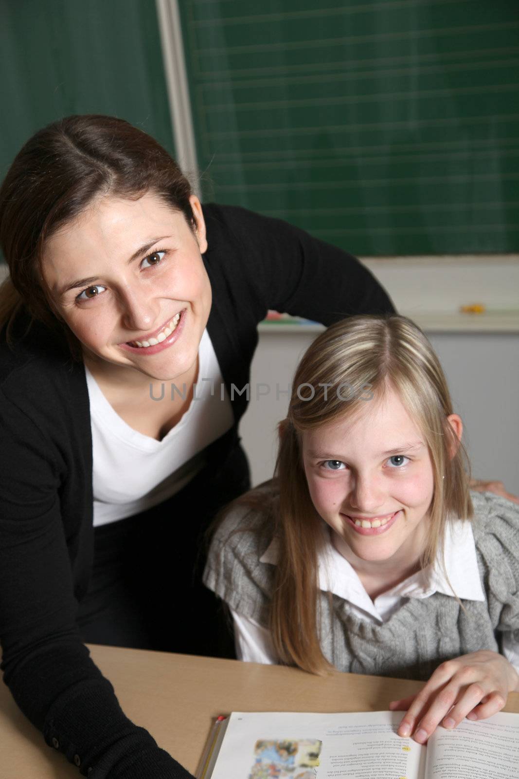 Cheerful teacher and student in the classroom with textbooks. by Farina6000