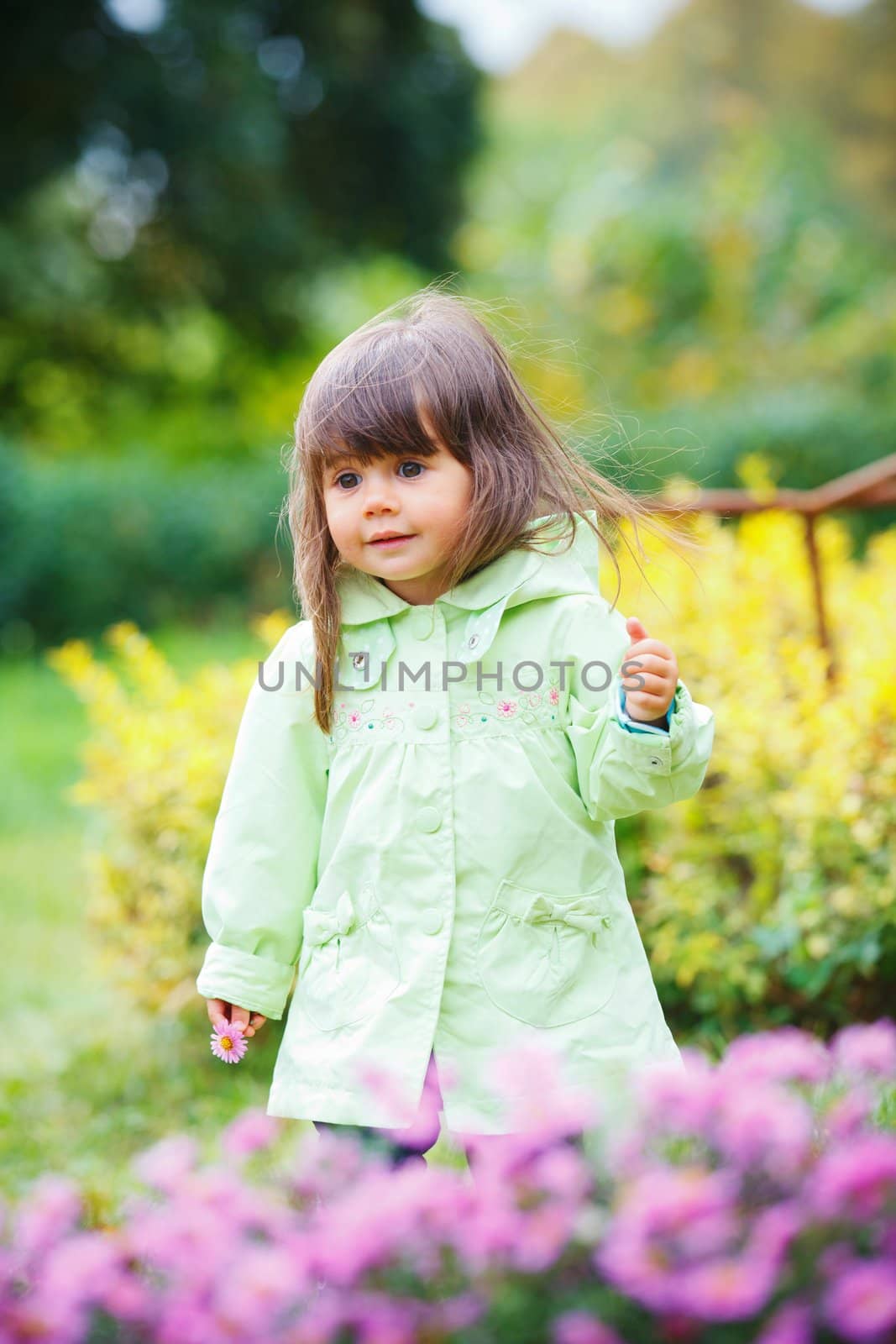 Clouse-up portrait pretty little girl in the park with a flower