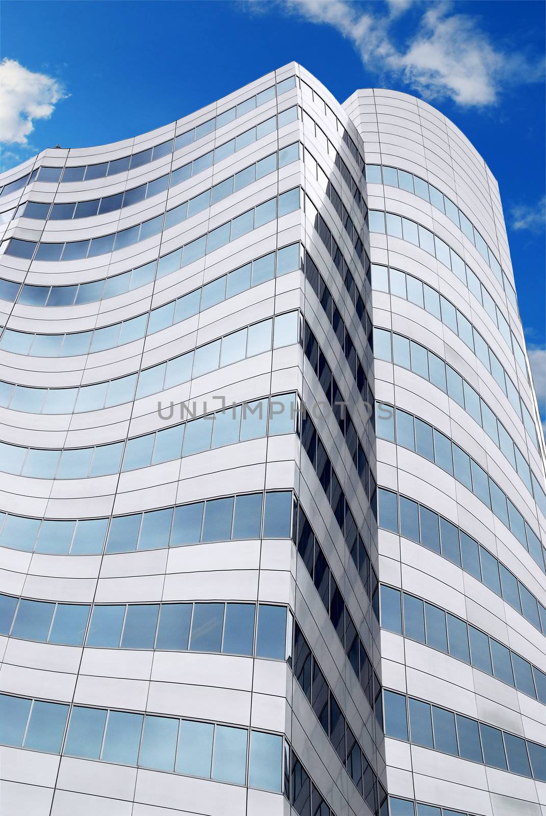 Futuristic corporate building with blue sky reflected in windows