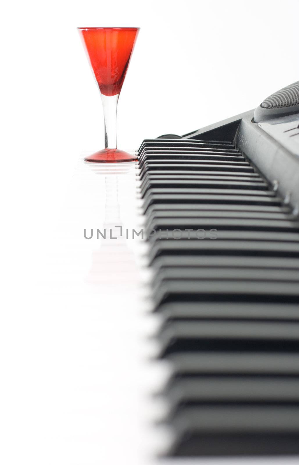 Piano keyboard and red glass on isolated background