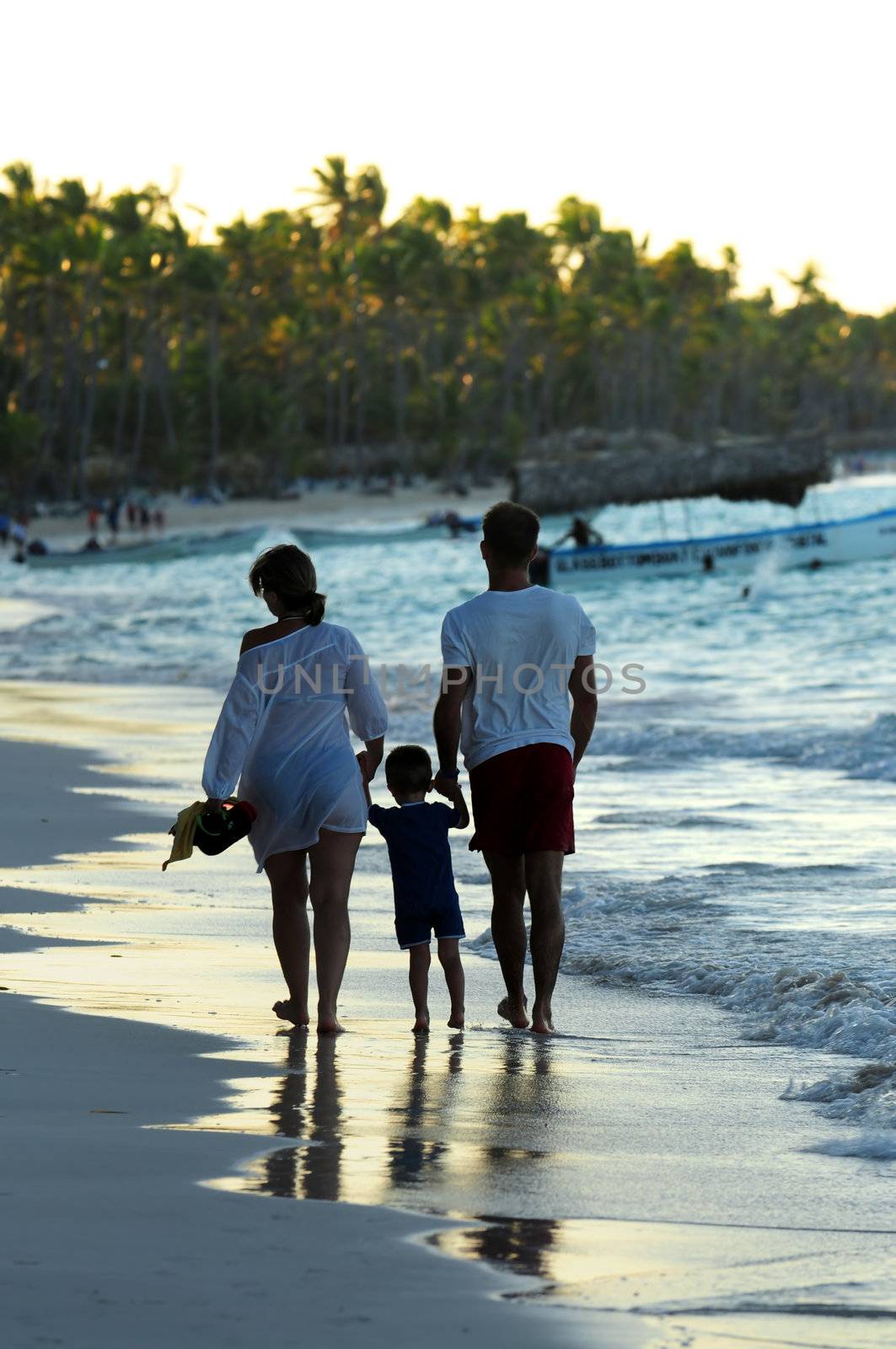 Family taking a walk on a sandy beach of tropical resort