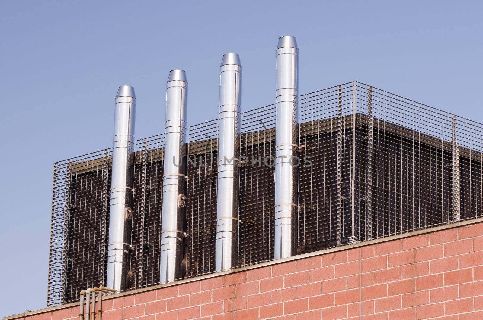 Four modern steel chimneys on a rooftop