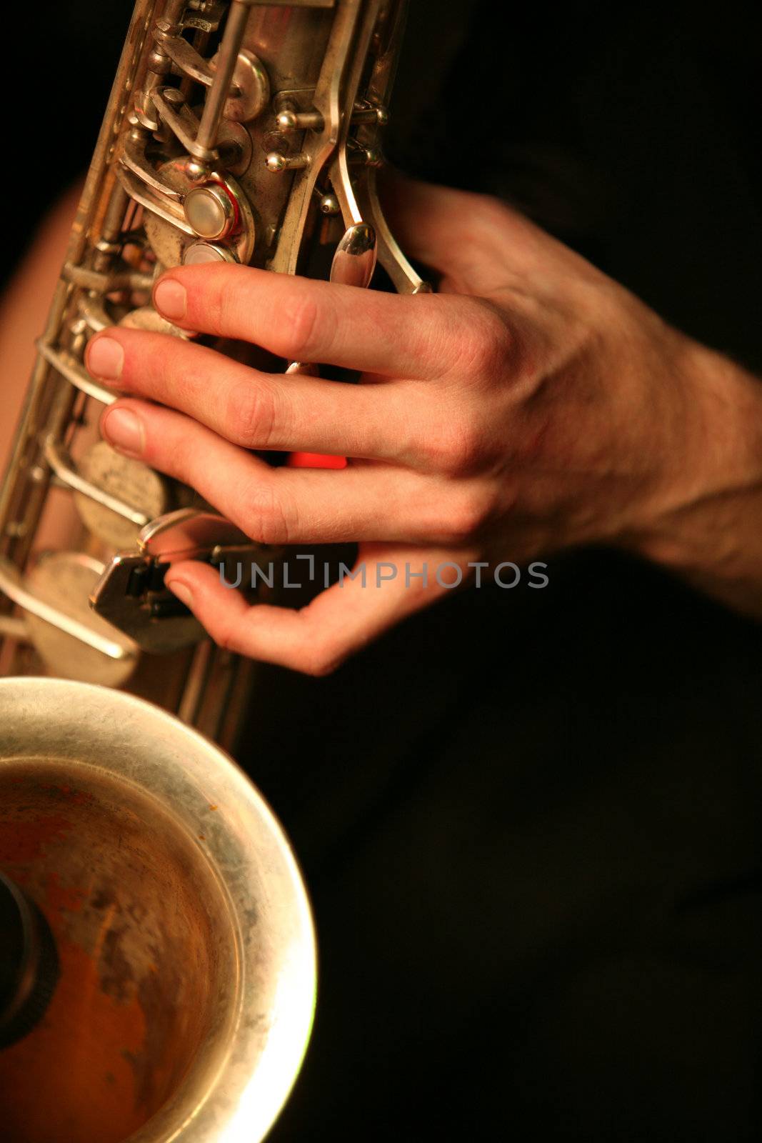 Hands of the saxophonist with a saxophone on a black background
