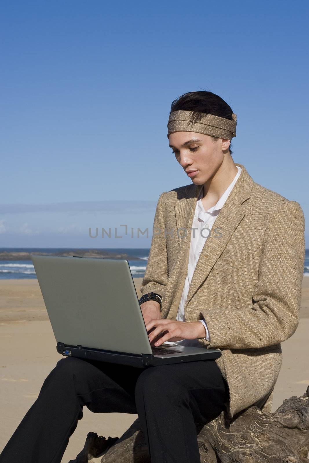 Young professional working on his laptop at the beach