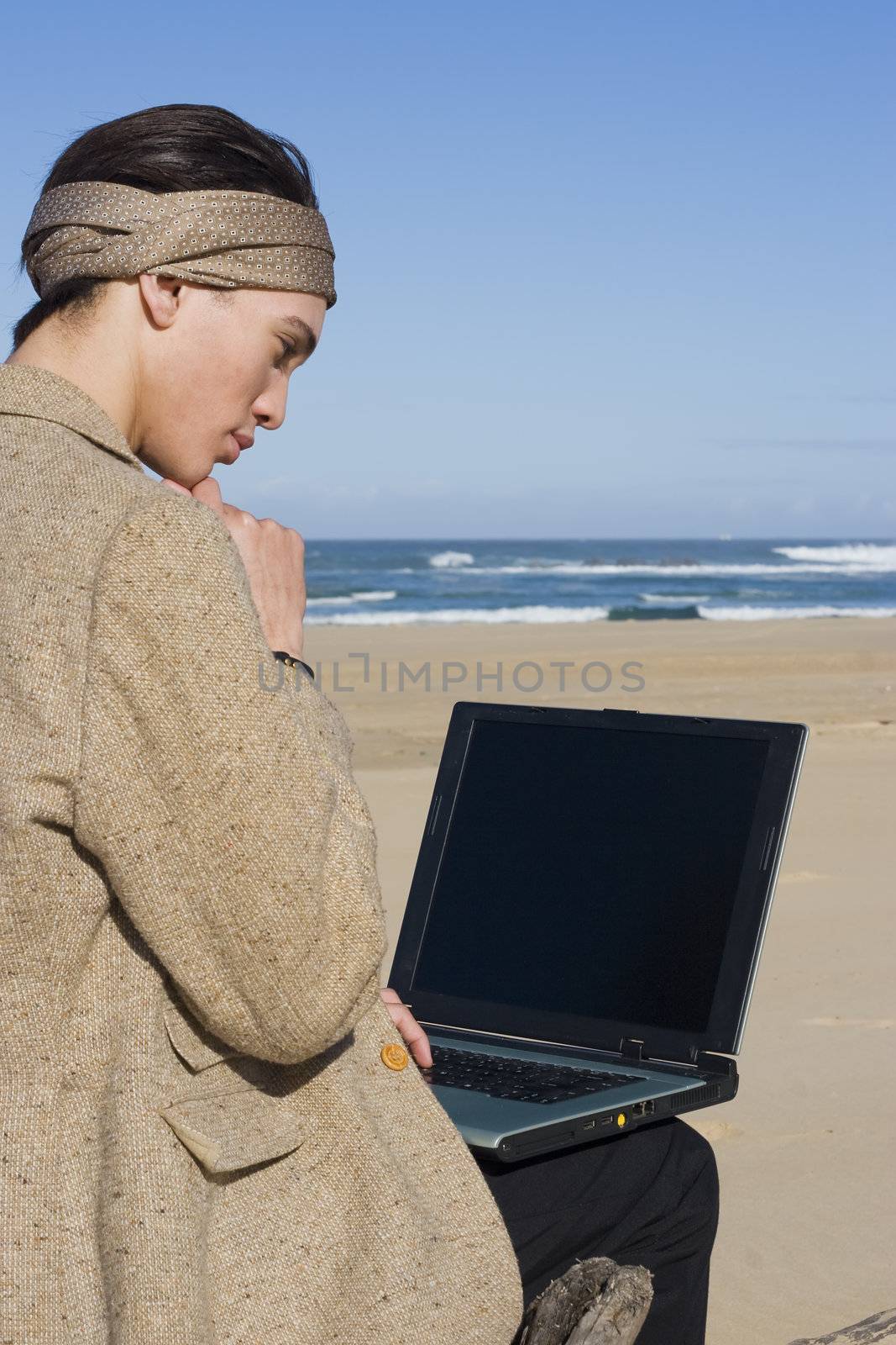 Young business professional on the beach with laptop