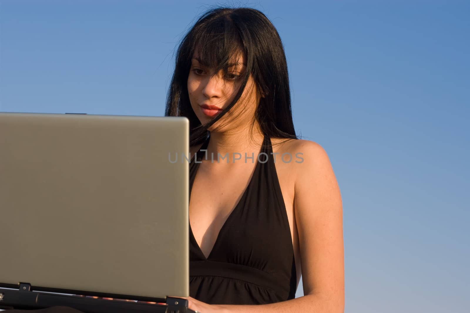 Attractive lady working on a laptop with blue sky background