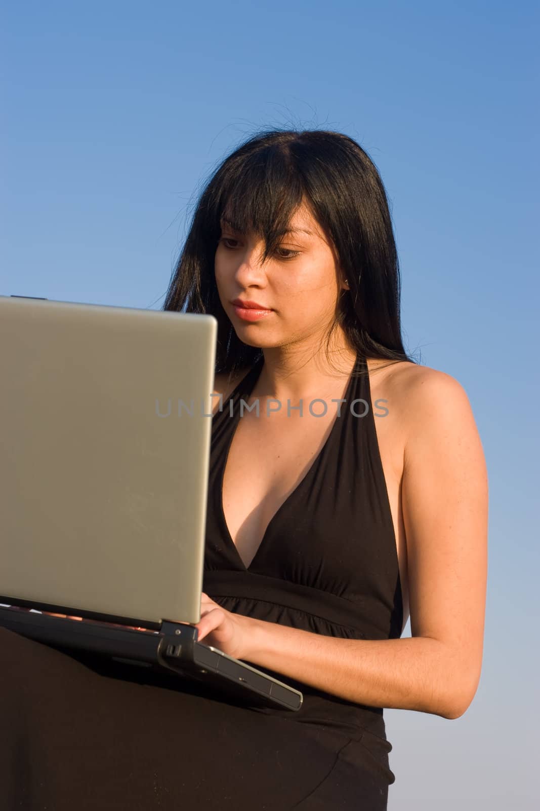Attractive woman working on a laptop with blue sky background