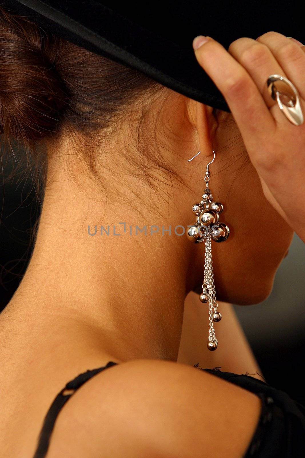 The image of the girl in rings and ear rings putting on a hat