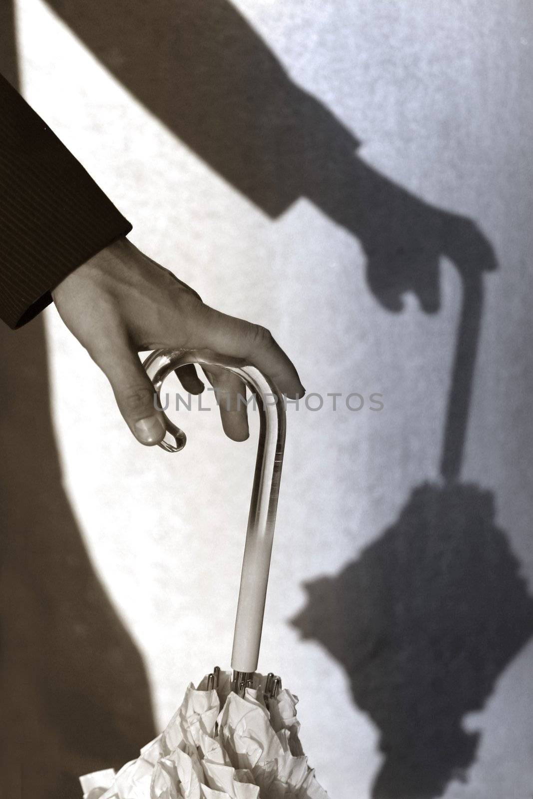 The man leans on the handle of a umbrella