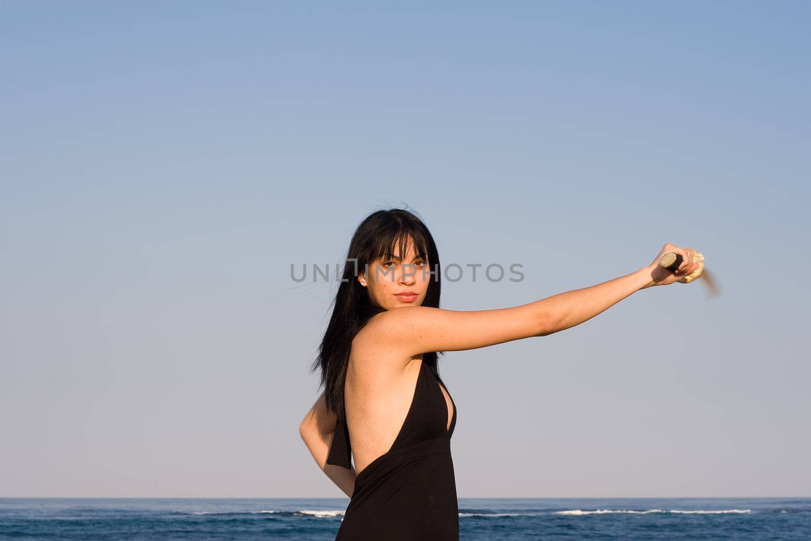 Asian model swinging a sword against blue sky