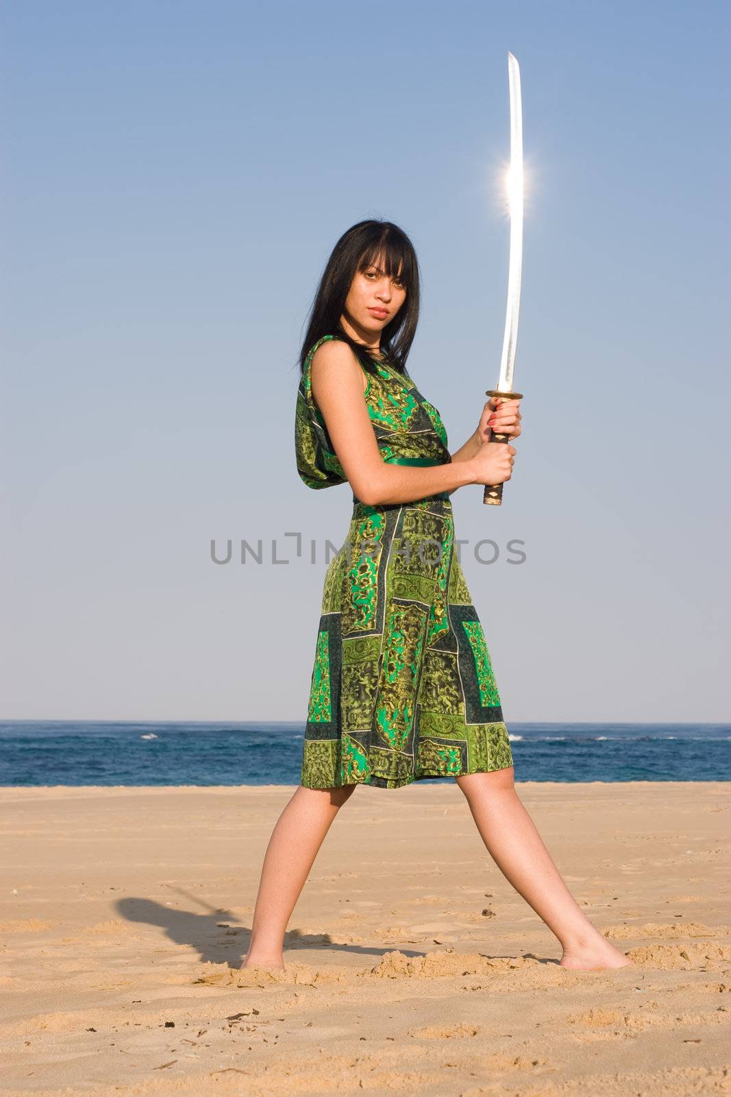 Ethnic model posing with a sword at the beach