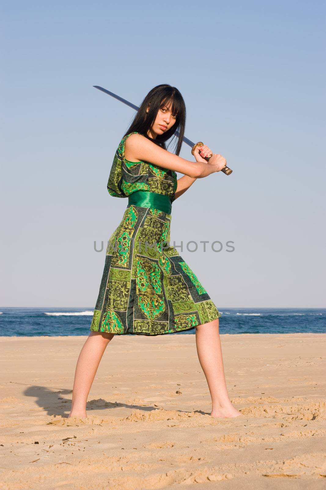 Ethnic Model posing with a sword at the beach